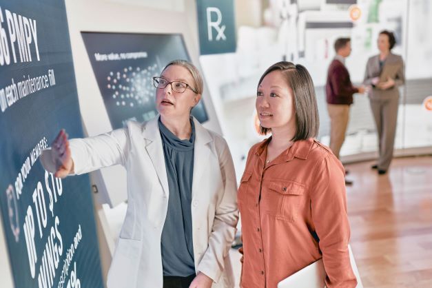 Pharmacist and woman looking at clinical poster.