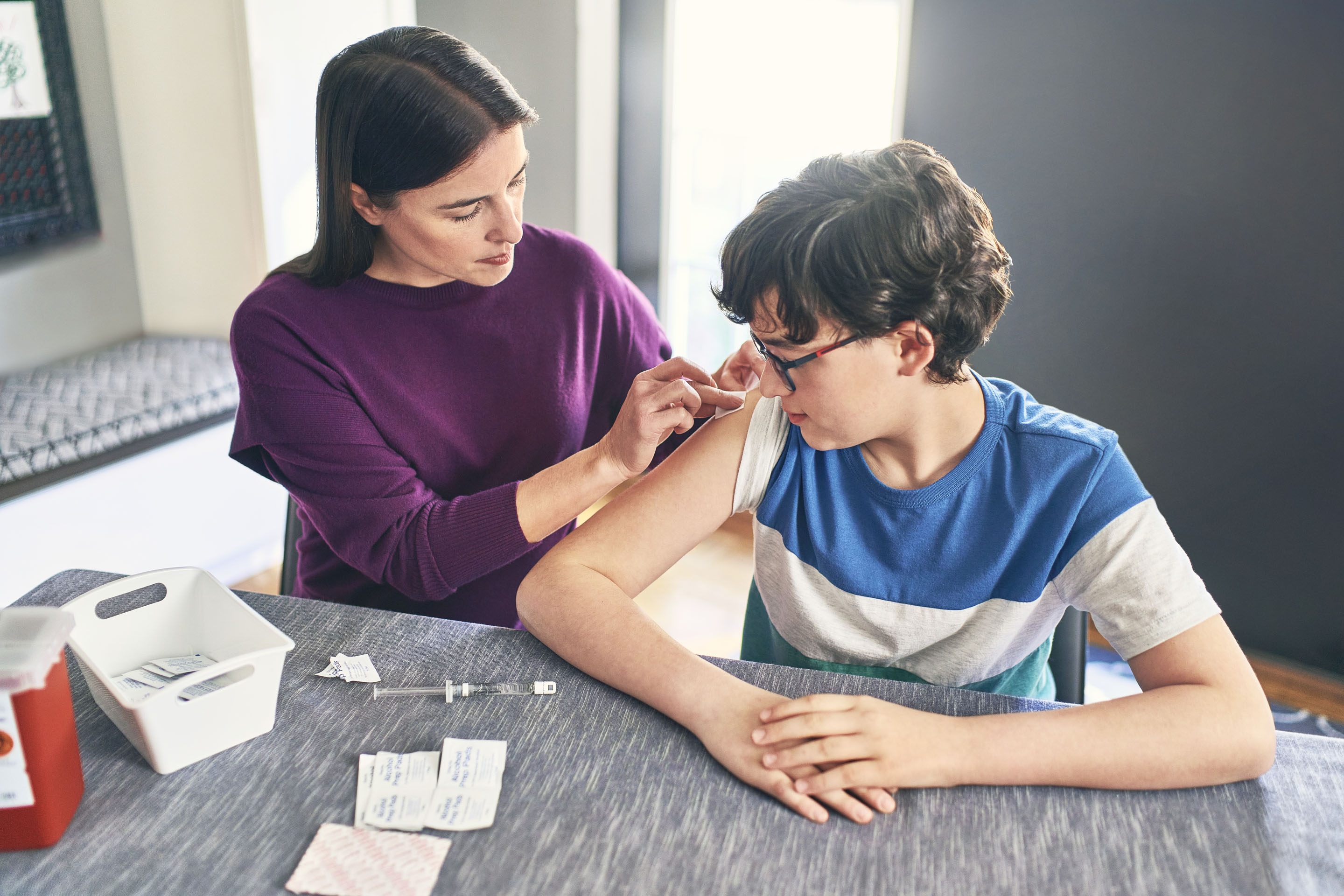 woman administering shot to young boy